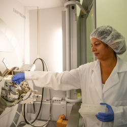 Female scientist in protective gear carefully does a system check on  mechanical equipment