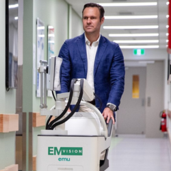 Medical professional pushes medical device on wheels through hospital hallway