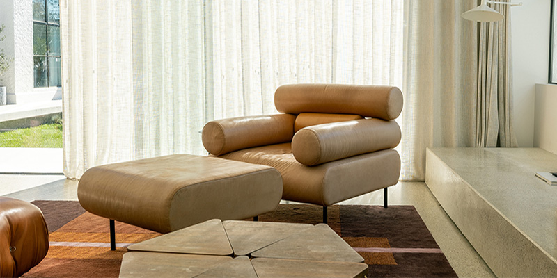 Tan upholstered armchair with a matching footstool in a living room.