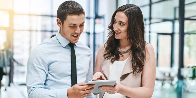 A man and woman in discussion, holding a notepad