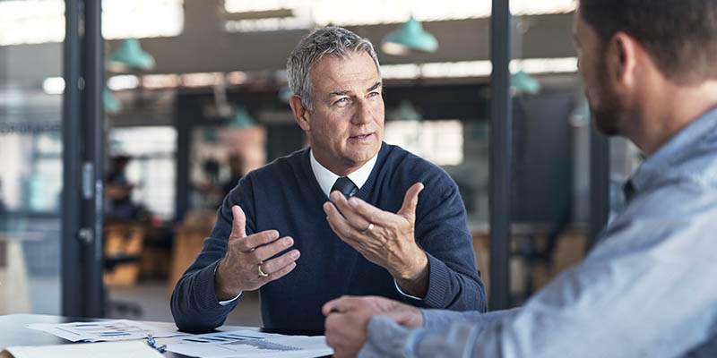 2 Caucasian business men sitting at an office desk